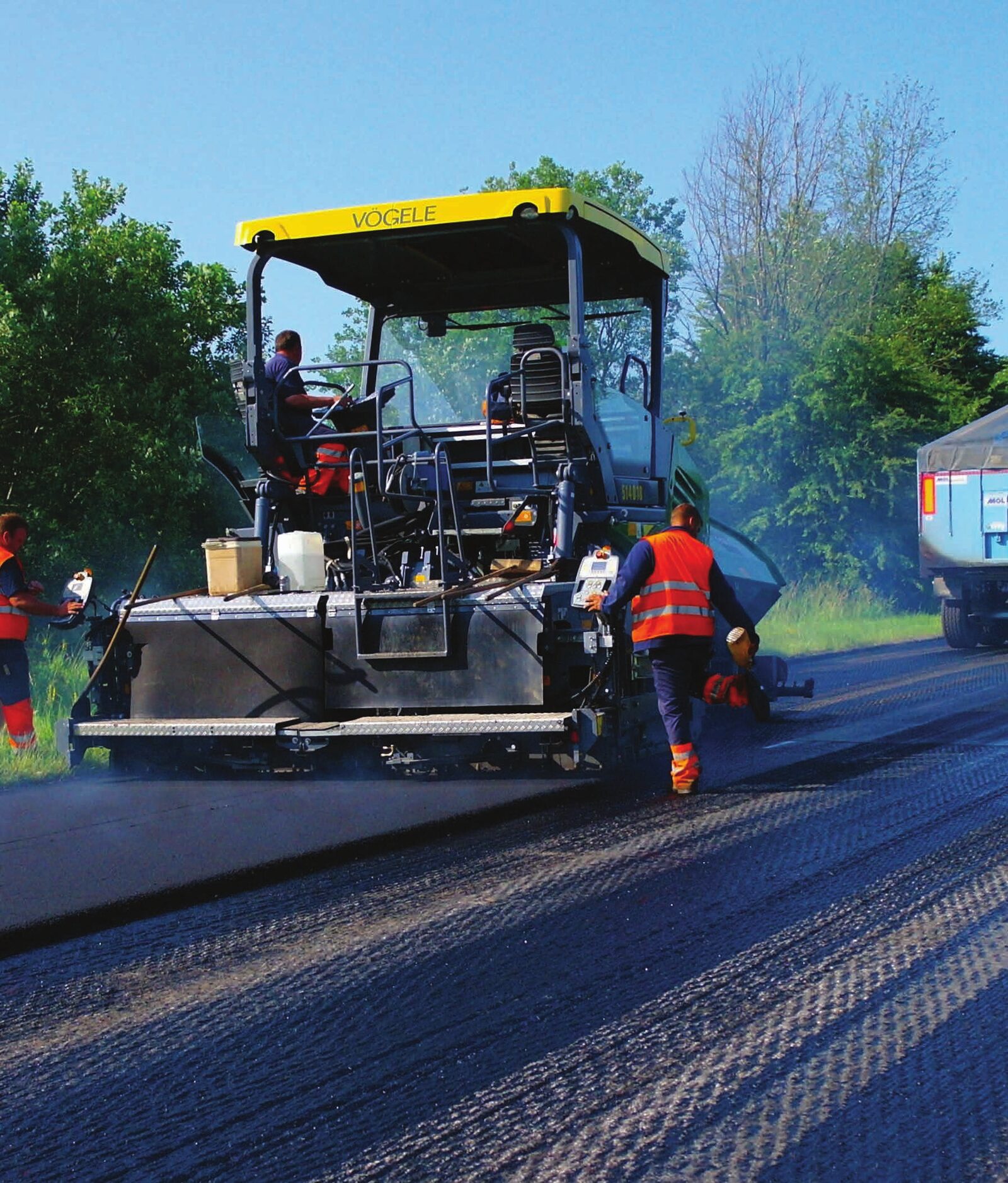 Asphalt paver and crew laying a fresh road surface